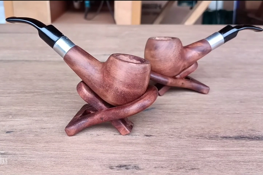 Due pipe in legno con vere metalliche appoggiate su poggiapipa di legno su un tavolo
